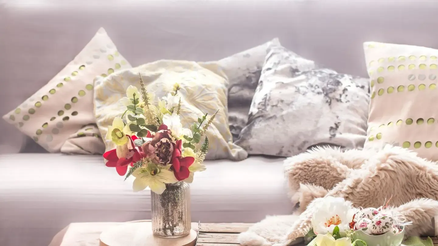 A vase of flowers is sitting on a table next to a couch.
