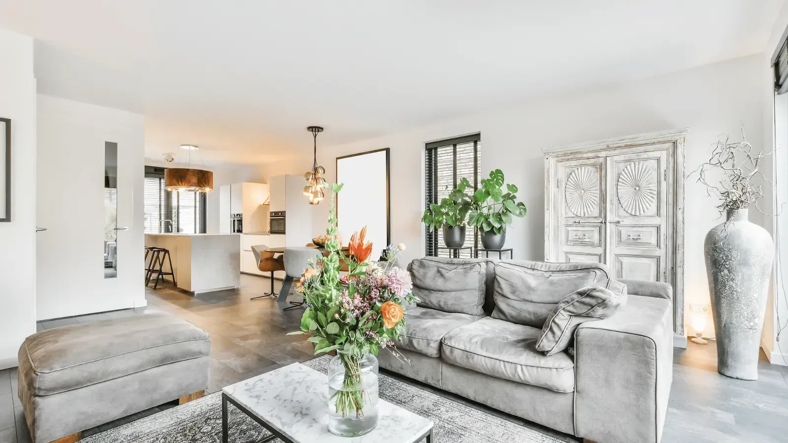 A living room with a couch , coffee table and vase of flowers.