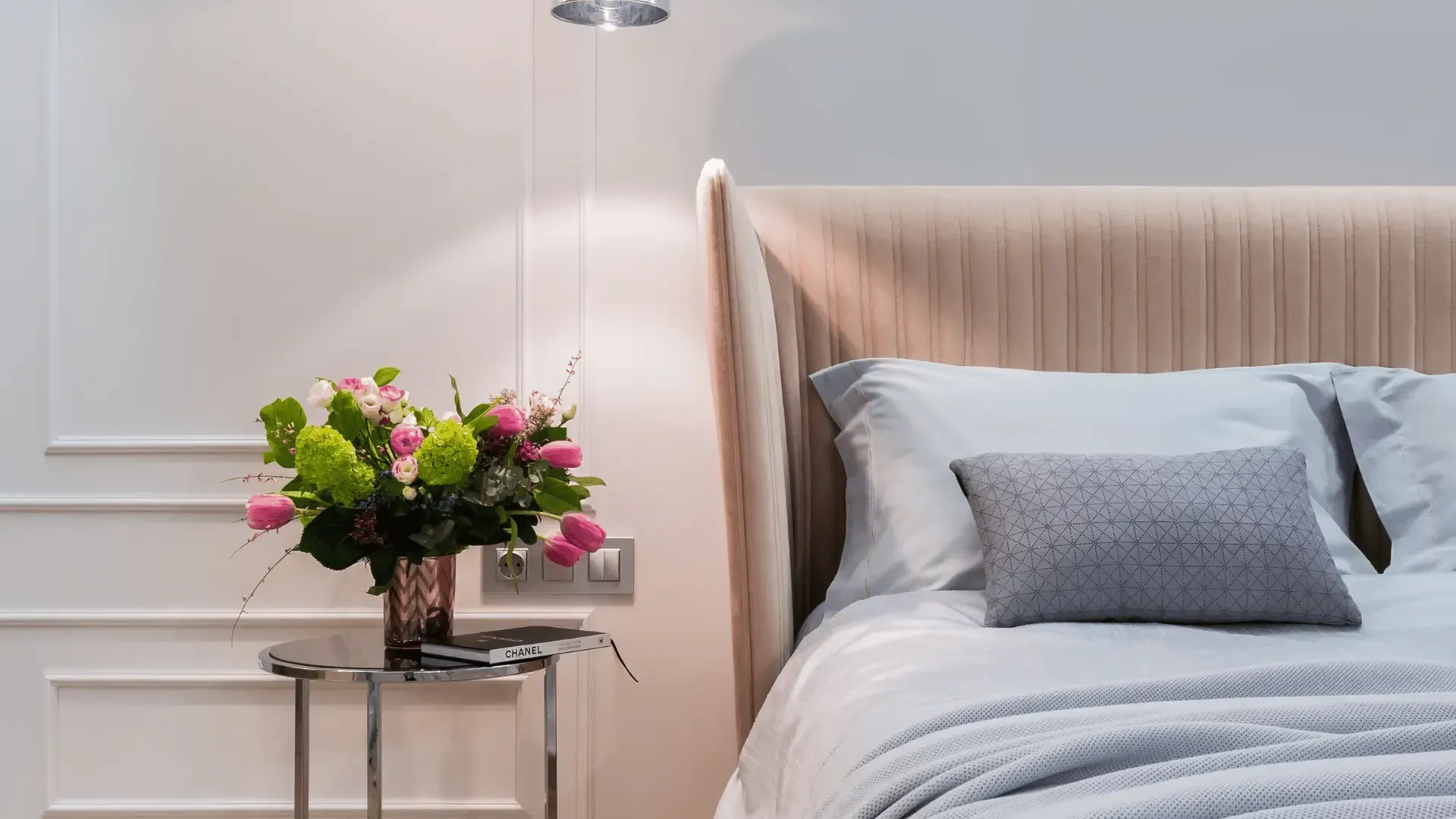 There is a vase of flowers on the nightstand next to the bed.