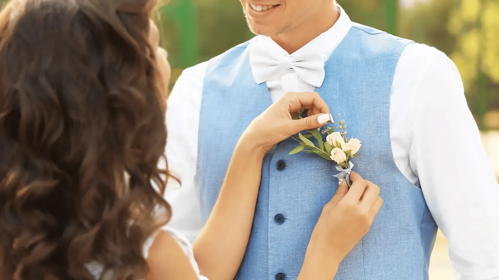A woman is putting a flower in a man 's pocket.