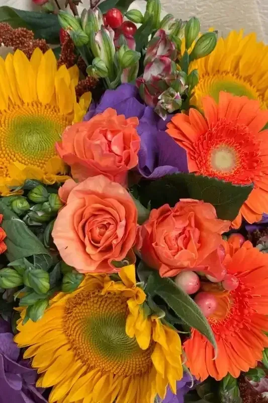 A close up of a bouquet of flowers with sunflowers and roses