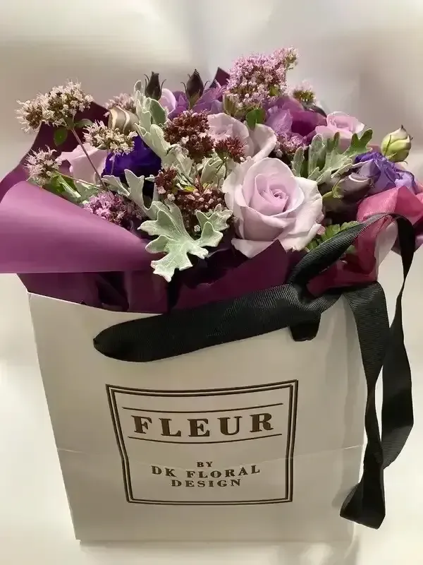 A white bag filled with purple and pink flowers