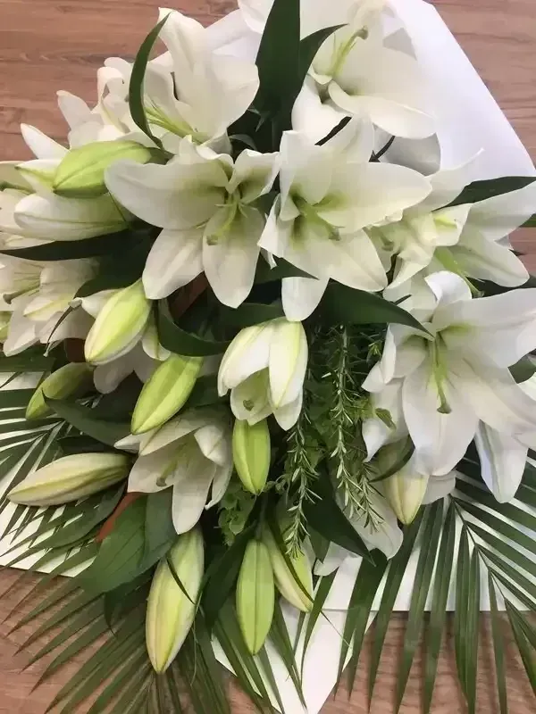a bouquet of white lilies sitting on top of a wooden table .