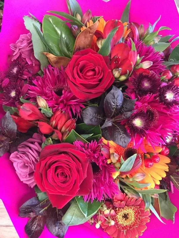 A close up of a bouquet of flowers on a pink background.