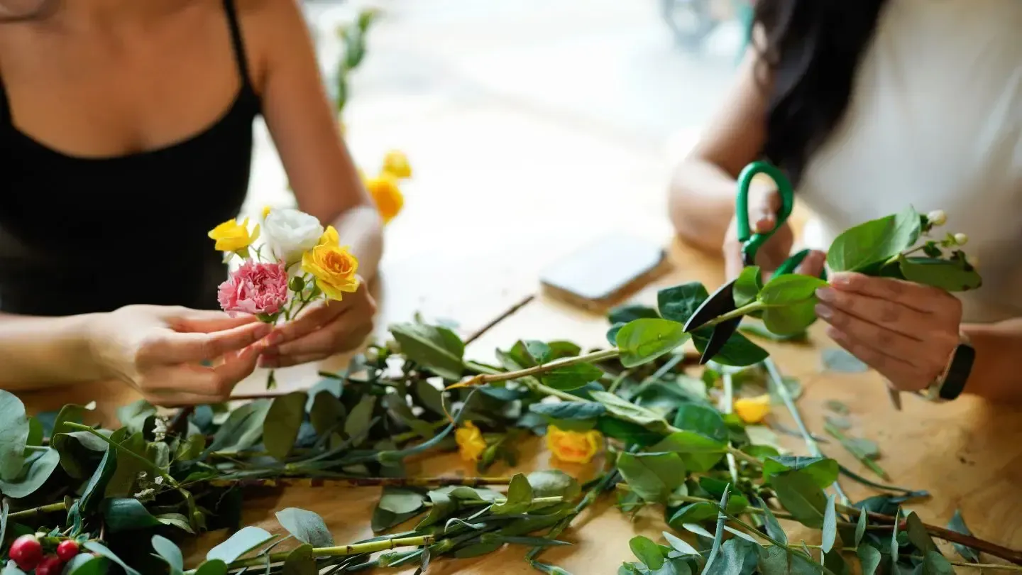 Florists arranging fresh bouquets with greenery and shears