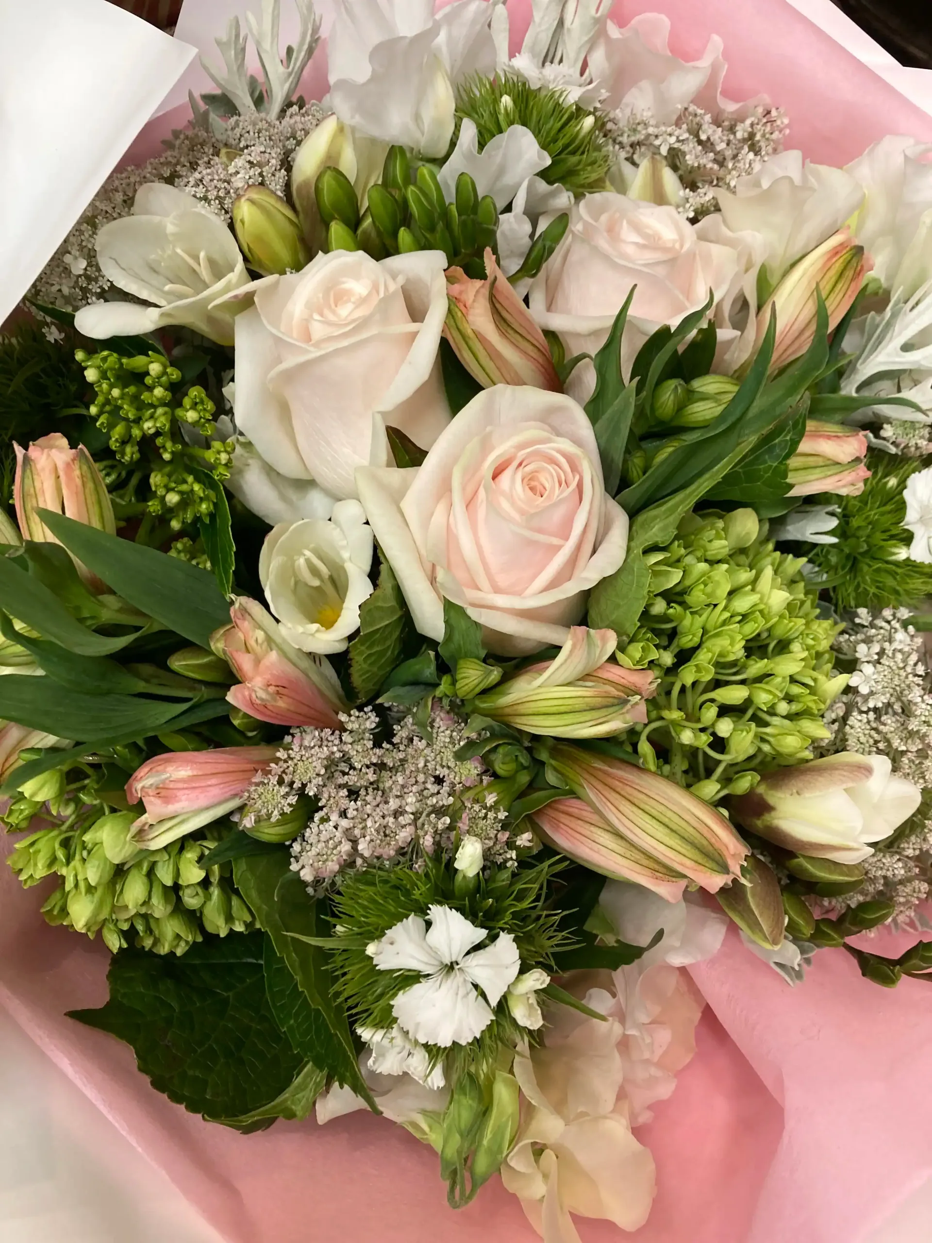 a close up of a bouquet of flowers wrapped in pink paper .