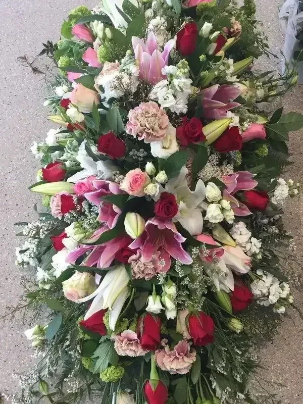 Floral arrangement with red roses, pink lilies, and white flowers.