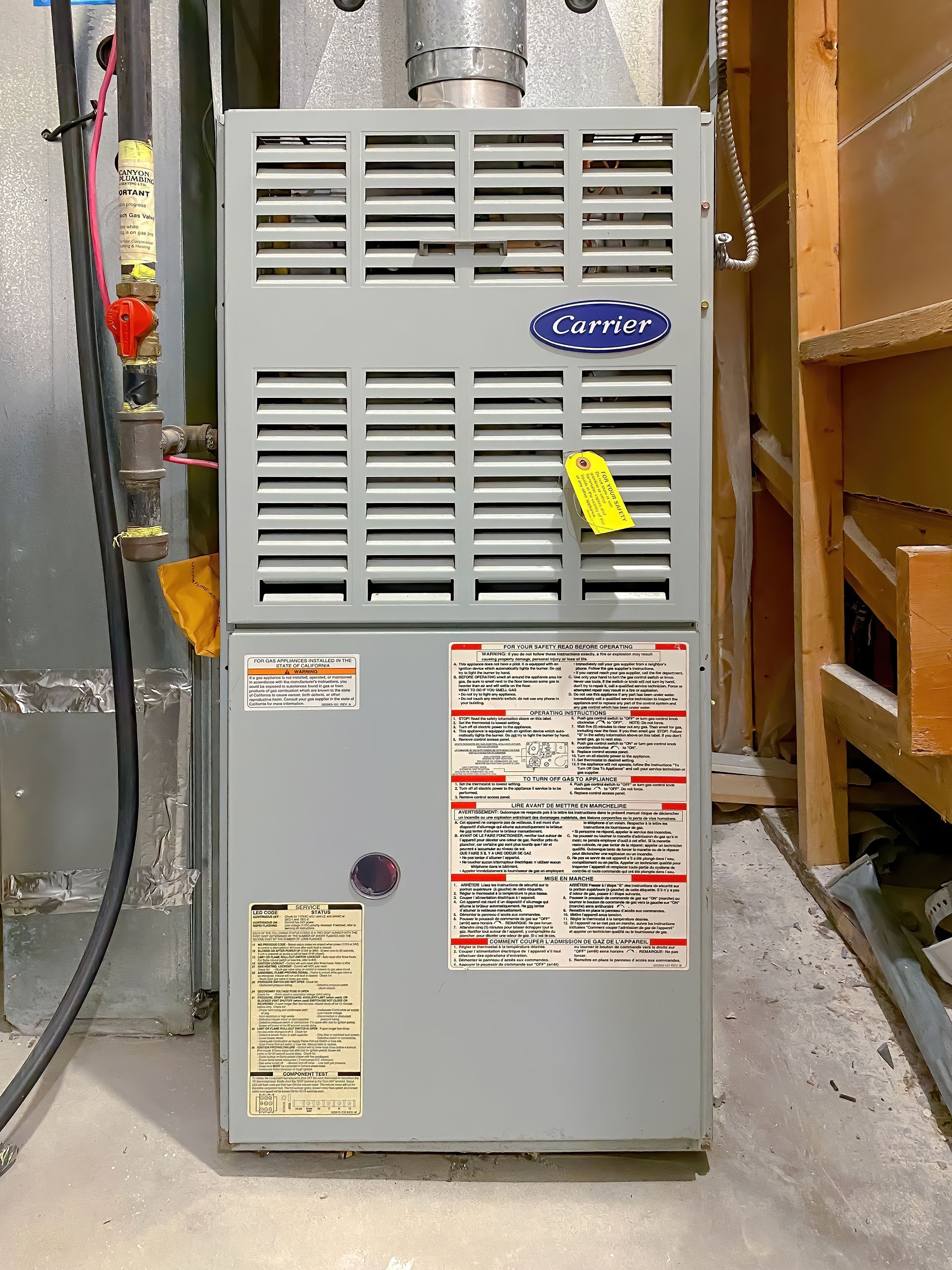 Gray Carrier furnace in a utility room with attached ductwork.