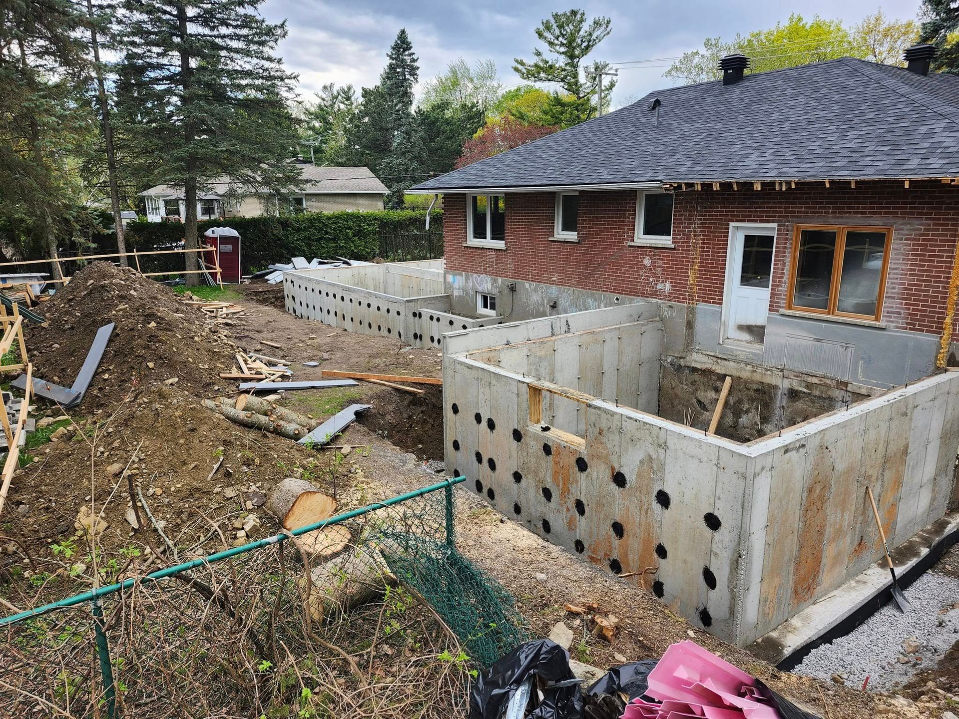 Nouveaux murs de fondation en béton pour une extension de maison en construction à côté d'une maison en briques existante.
