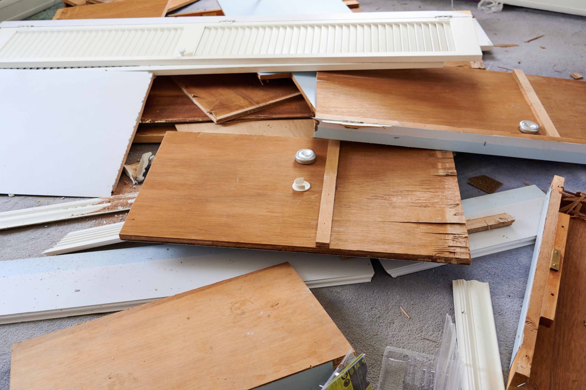 Pile of wooden debris, including boards, panels, and a vent cover, likely from a demolition.