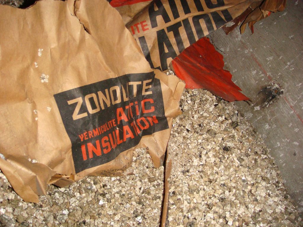 Un sac en papier brun étiqueté « Isolation de grenier Zonolite » déchiré recouvre l'isolant granulaire.