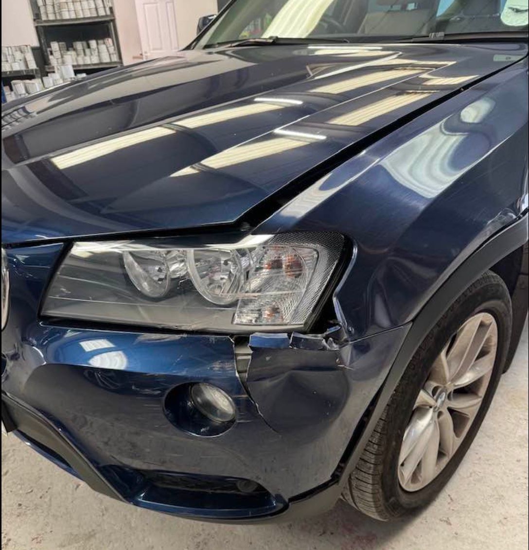 a blue car with a damaged front bumper and hood