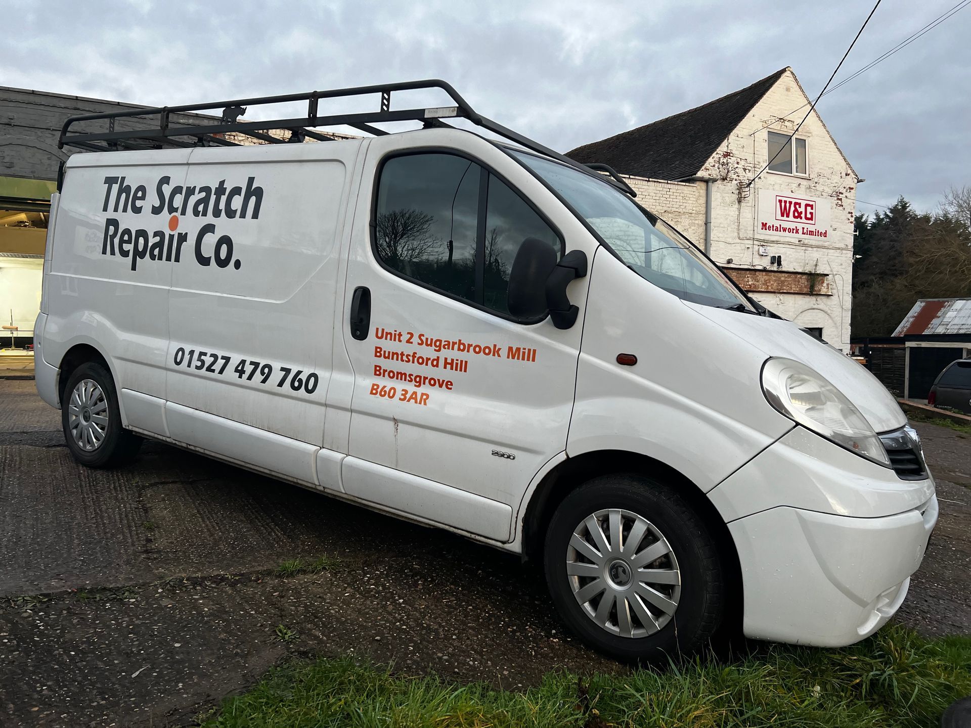 a white van for the scratch repair company is parked in front of a building