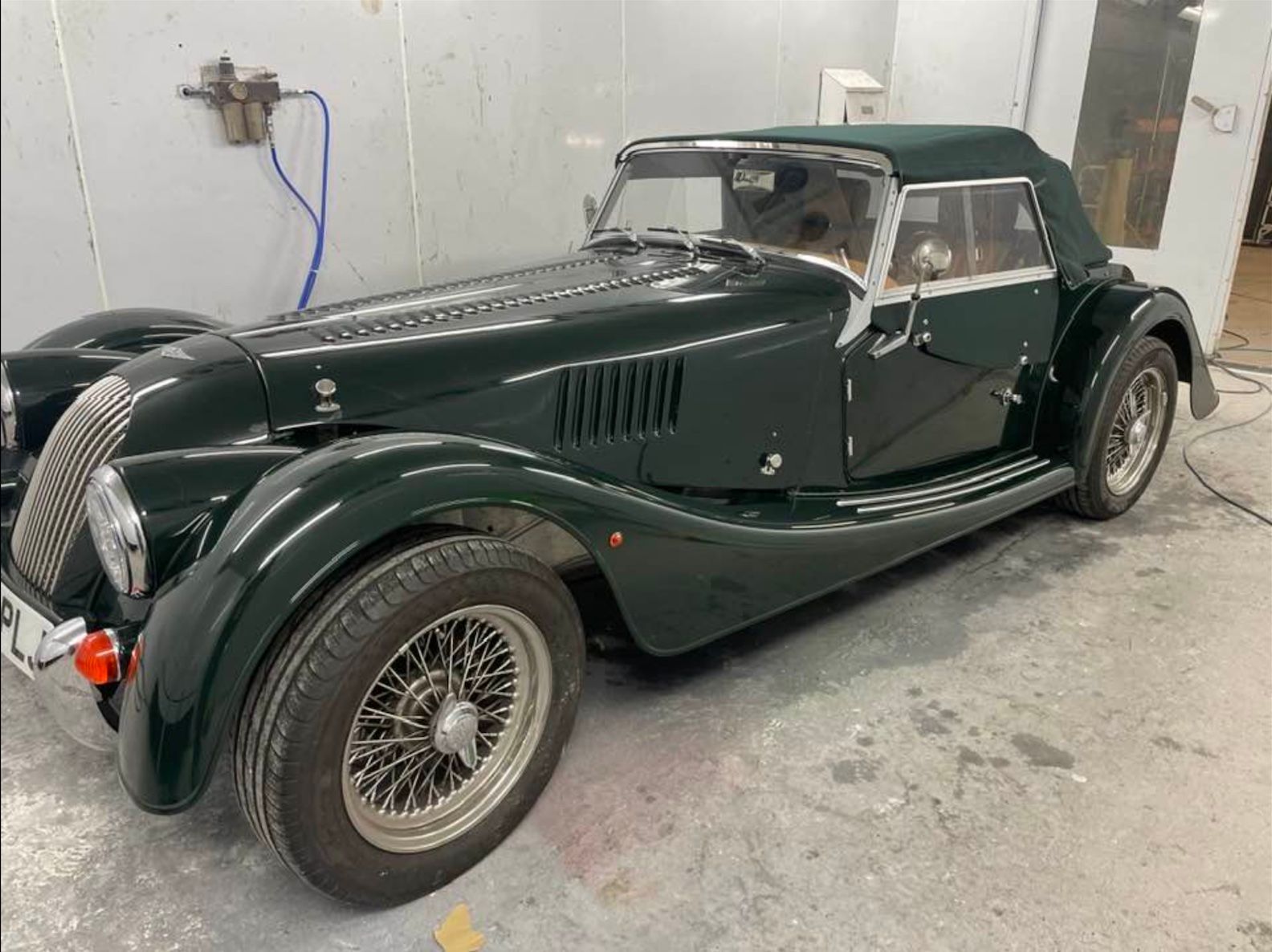 a green sports car is parked in a garage .