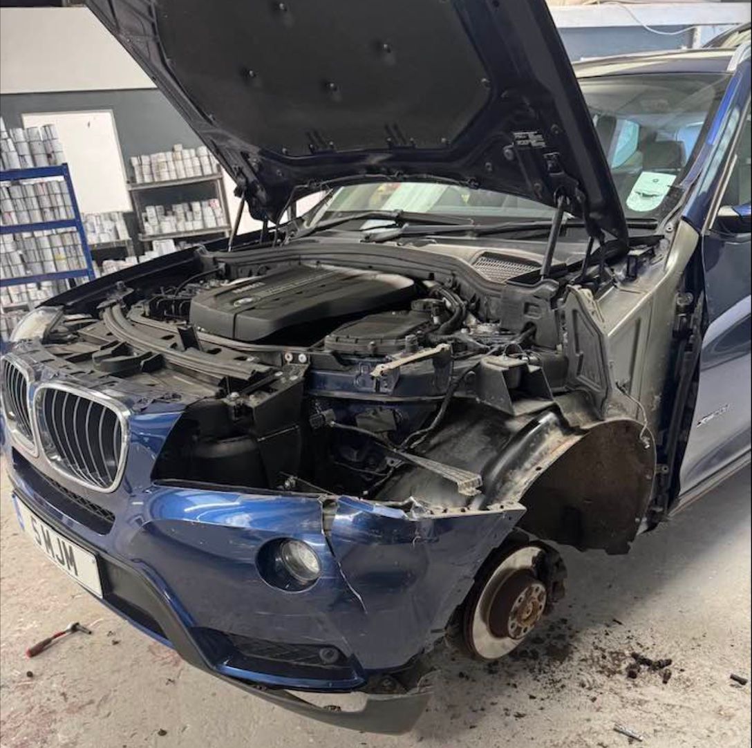 a blue car with the hood open is parked in a garage .