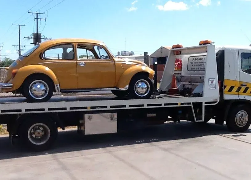 Yellow Beetle Car Being Towed on a Yellow Tow Truck Bed — Prompt Tilt Tray Towing & Recovery in Pine Creek, NT