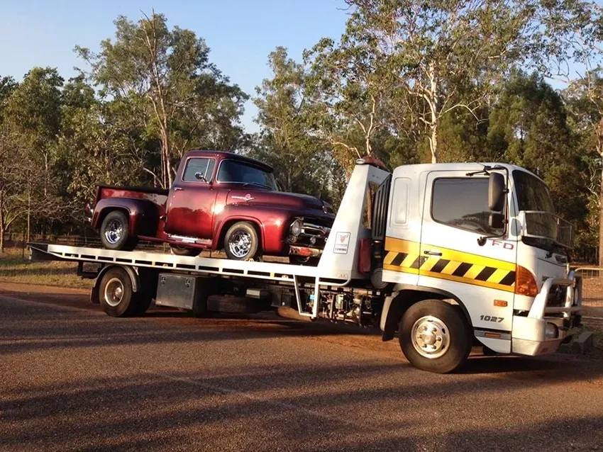 A Red Retro Truck on a White Tow Truck on a Road — Prompt Tilt Tray Towing & Recovery in Palmerston, NT