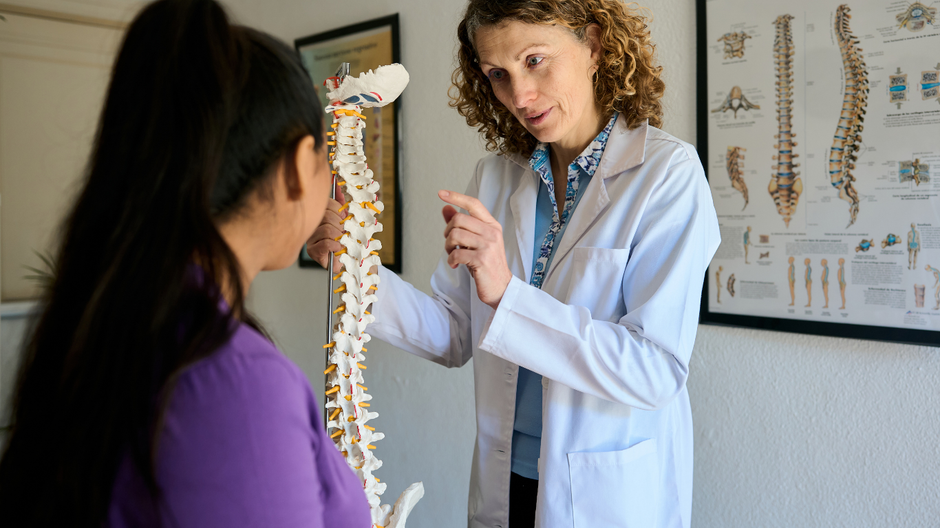 Doctor explaining a spine model to a patient in a clinic office