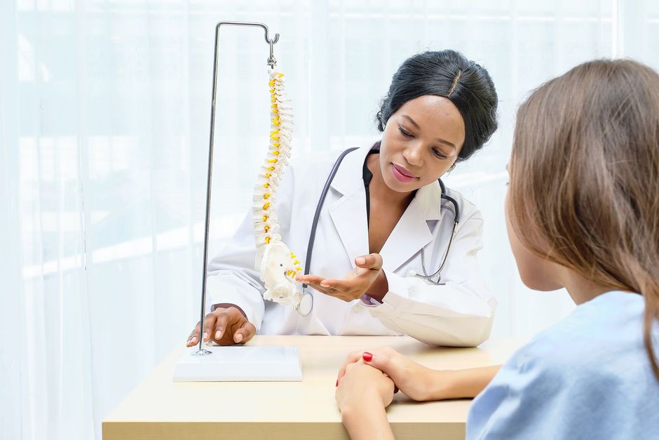 Doctor examining a patient’s back pain in a bright clinic room