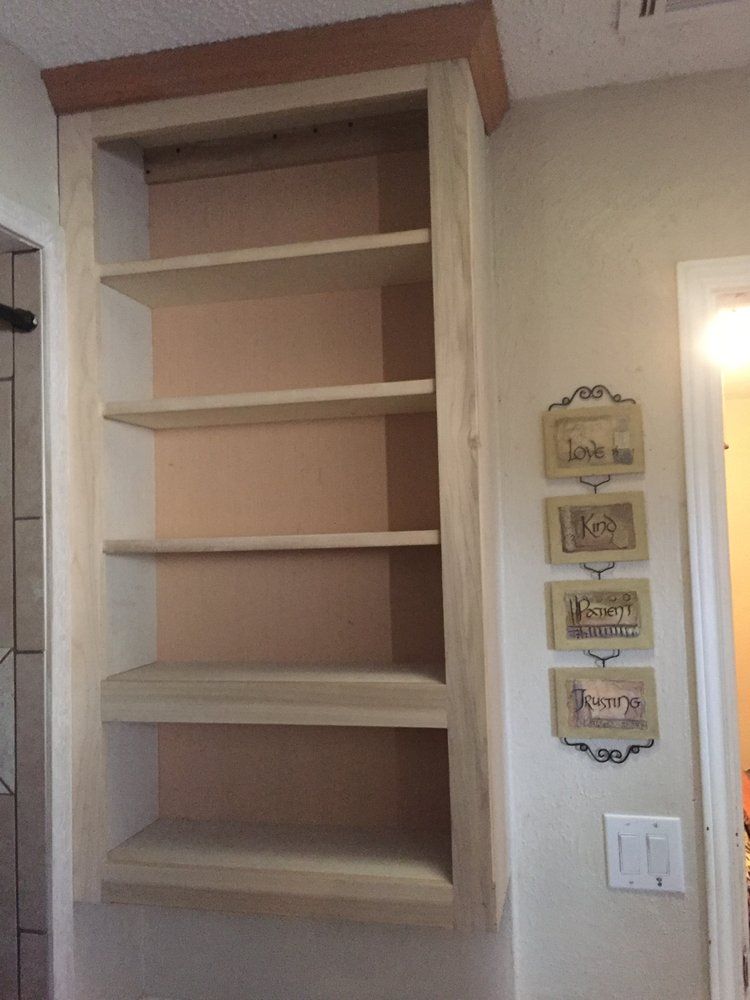 A wooden bookshelf is sitting on a wall next to a door.
