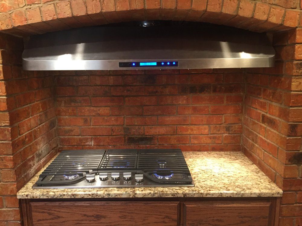 A stove top oven is sitting in a kitchen next to a brick wall.