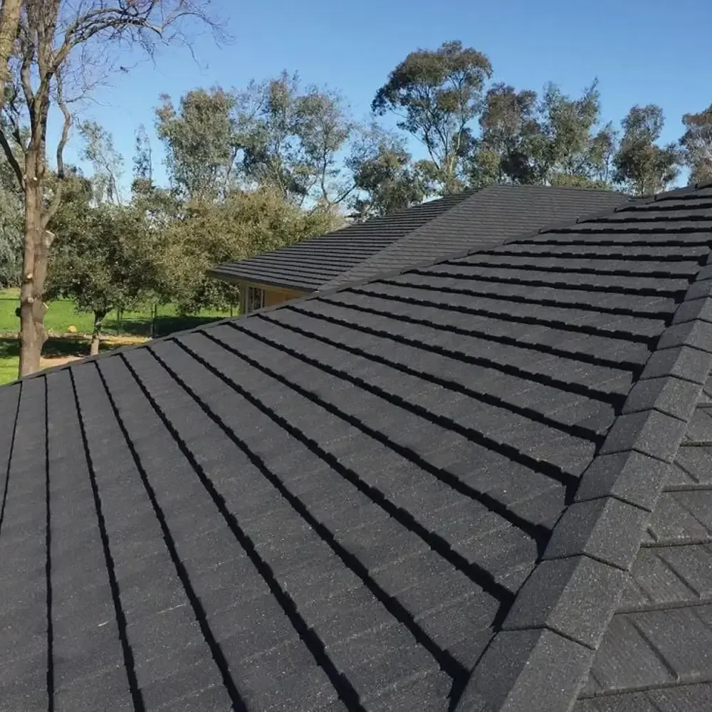 A black tiled roof with trees in the background