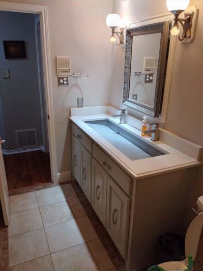 A bathroom with a sink , mirror and toilet.