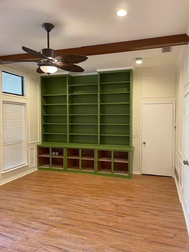 A living room with green shelves and a ceiling fan.