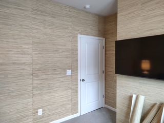 Empty room with beige textured walls, white door, and wall-mounted TV