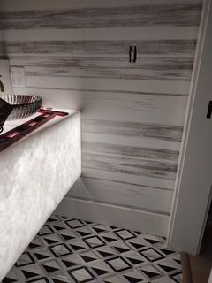 Modern bathroom with patterned black-and-white tile, white vanity, and gray striped walls.