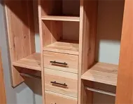 Wooden closet organizer with shelves, drawers, and hanging rods.
