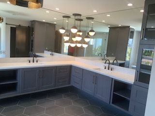 Modern kitchen with dark blue cabinets, white countertops, hexagon tile floor, and pendant lights