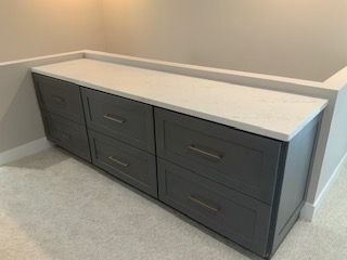 Dark gray bathroom vanity with white countertop against beige walls and carpeted floor
