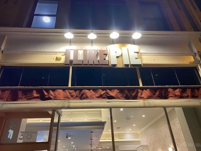 Storefront sign reading “LITE PIE” above a shop entrance at night.