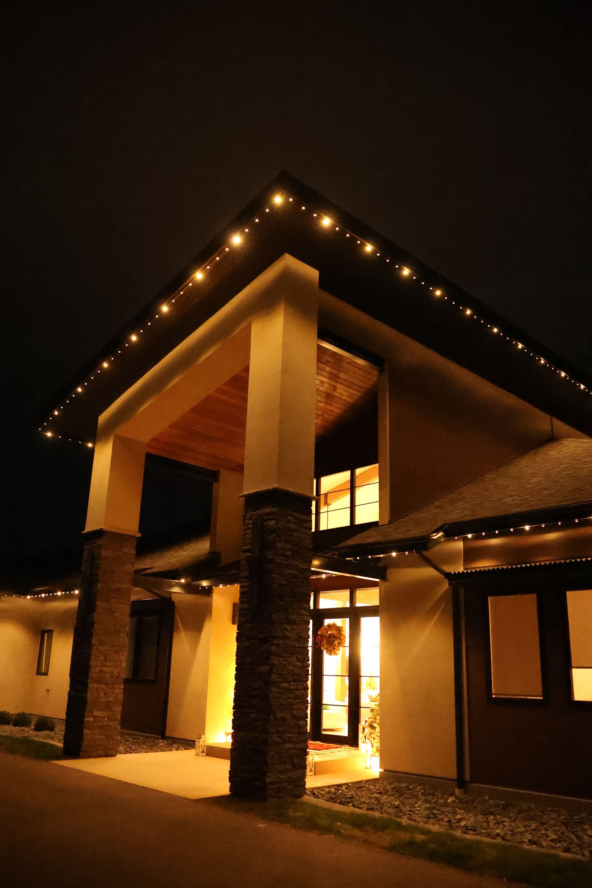 Illuminated modern building entrance at night with peaked roof and warm lights