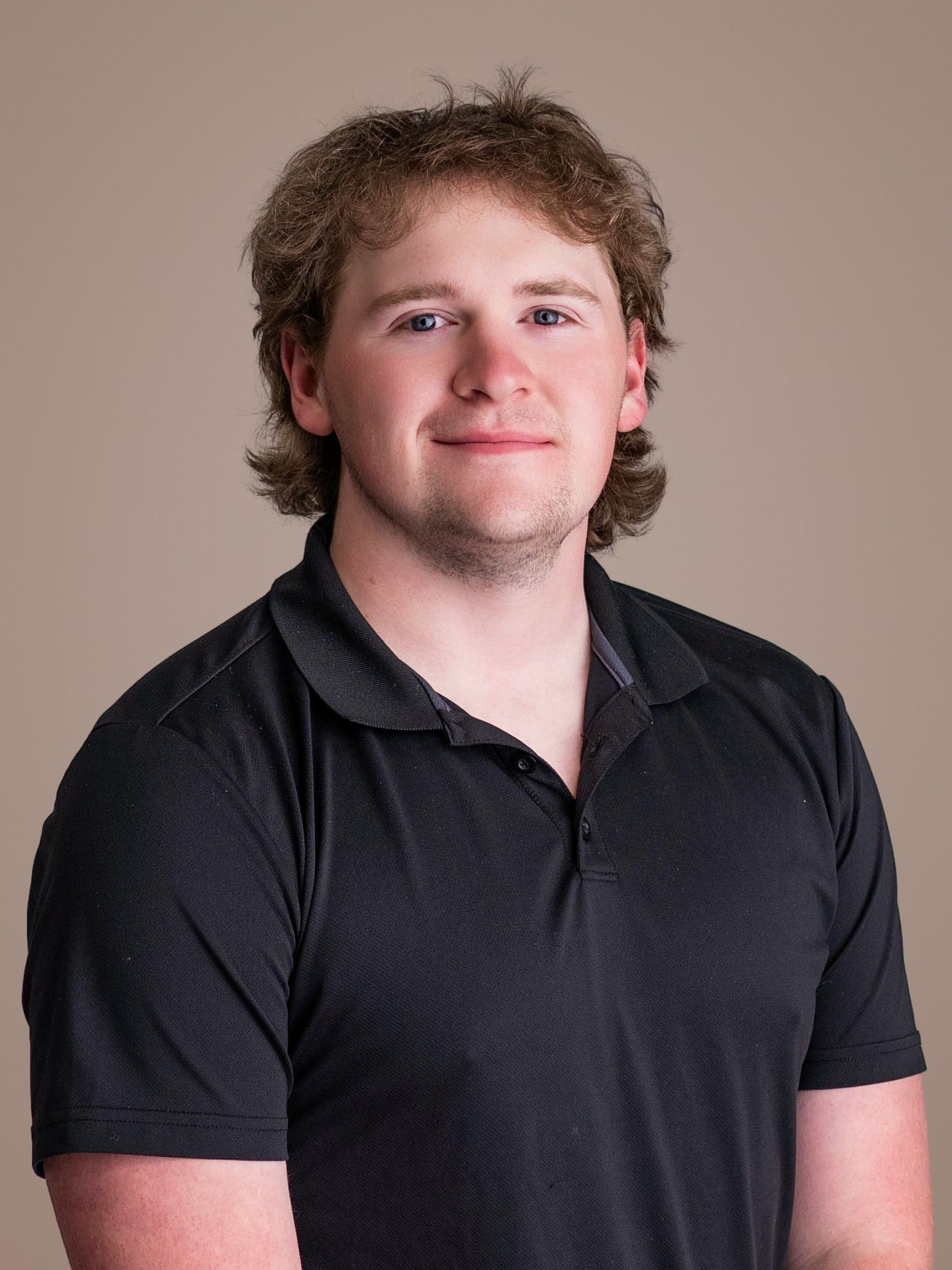 Portrait of a person in a dark polo shirt against a plain beige background