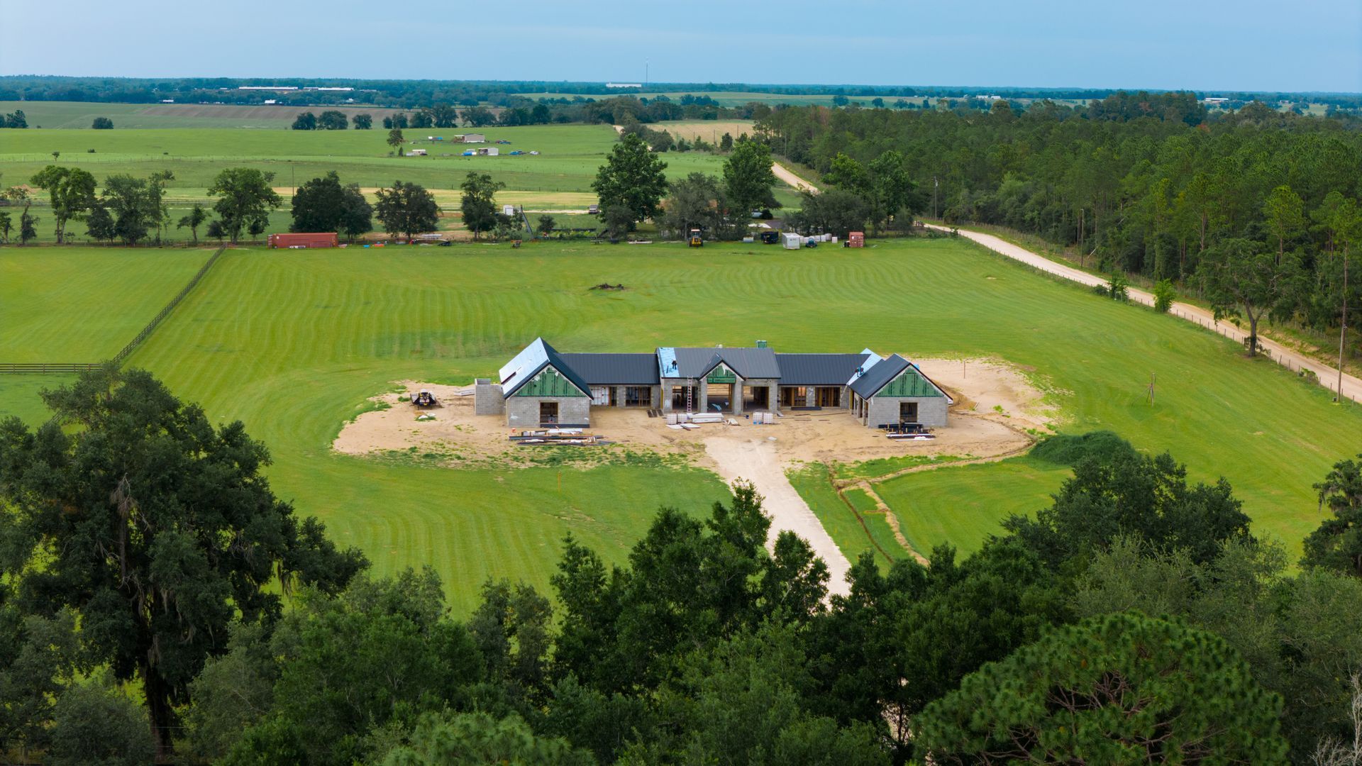 Aerial view of a farmhouse with outbuildings surrounded by green fields and trees