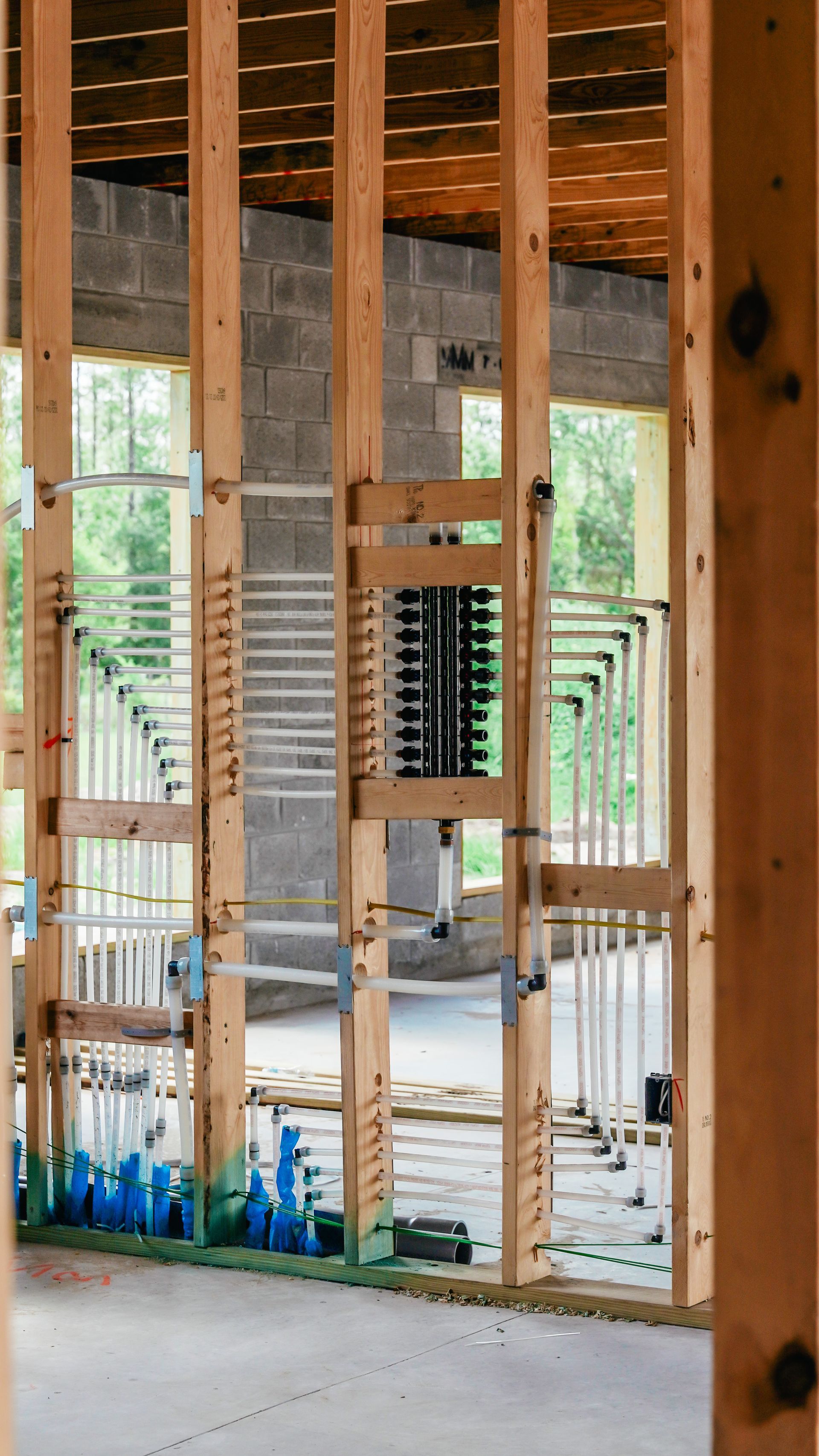 Wood-framed building interior with exposed studs, unfinished floors, and daylight through large openings