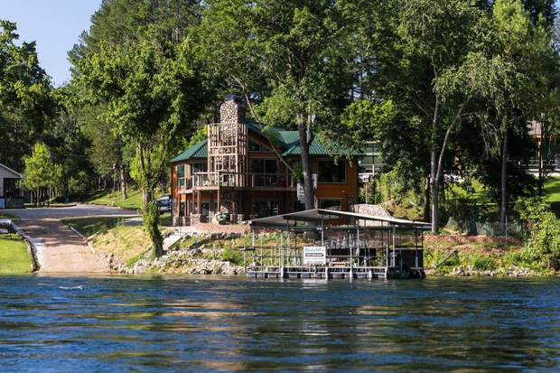 Lakeside cabin among trees with a dock and calm water in the foreground