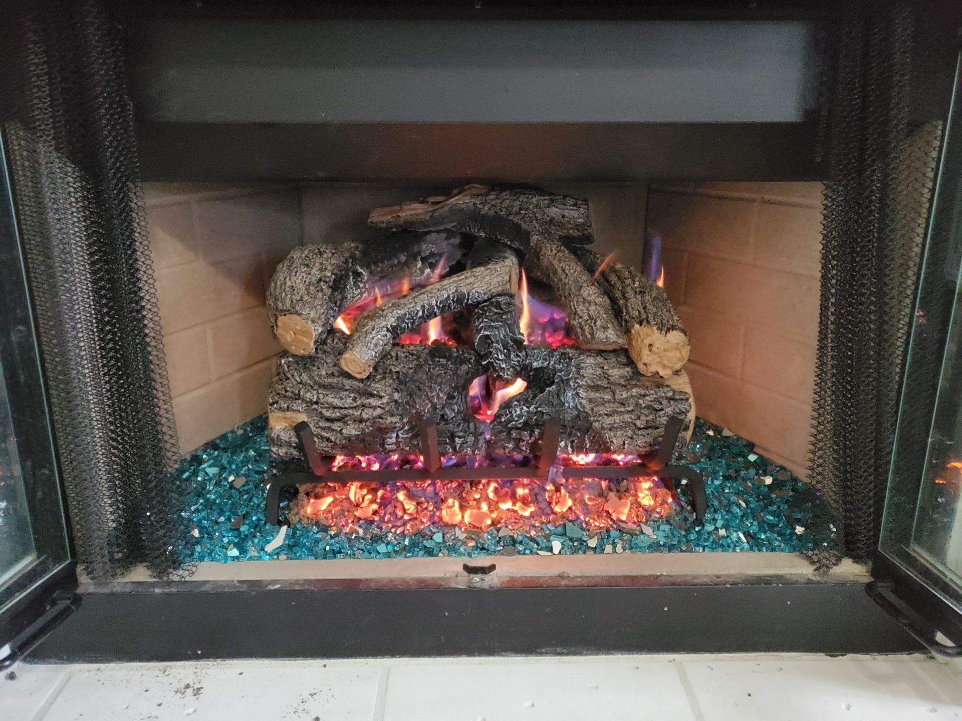 A fireplace filled with logs and fire glass.