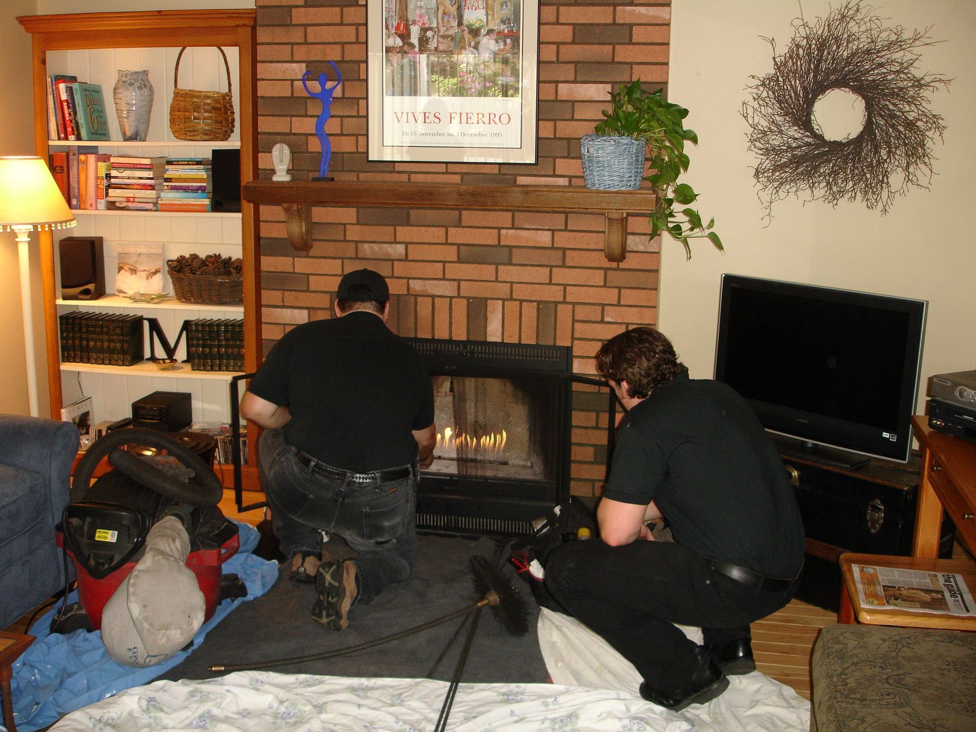 Two men are working on a fireplace in a living room