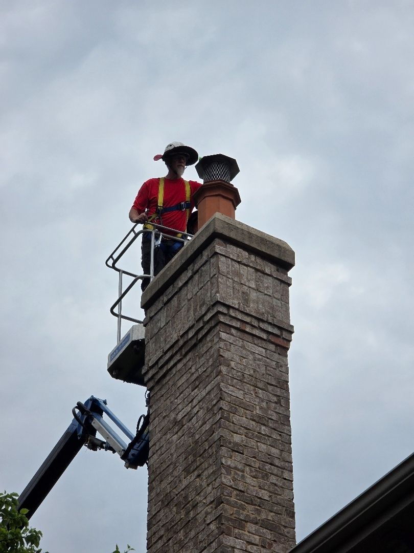 A man is standing on top of a brick chimney.