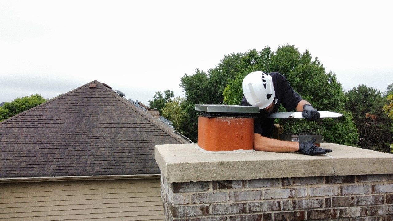 A man is standing on top of a brick chimney. A man is standing on top of a brick chimney.