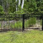 Black metal fence in front of greenery.