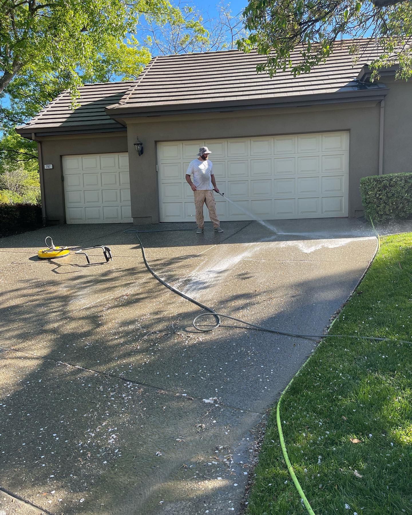 A man is standing in front of a garage with a hose.