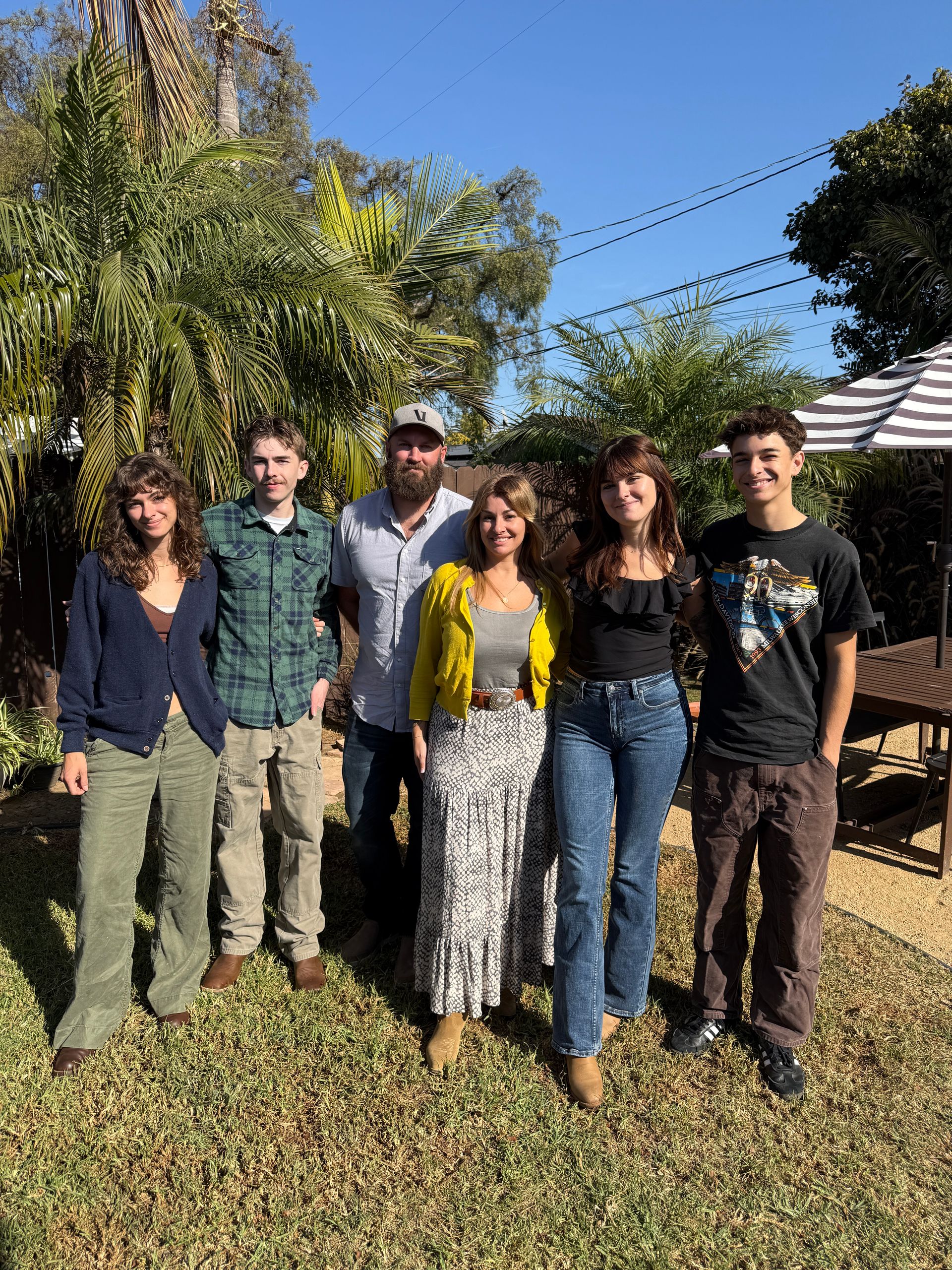 A group of people are posing for a picture in a backyard.