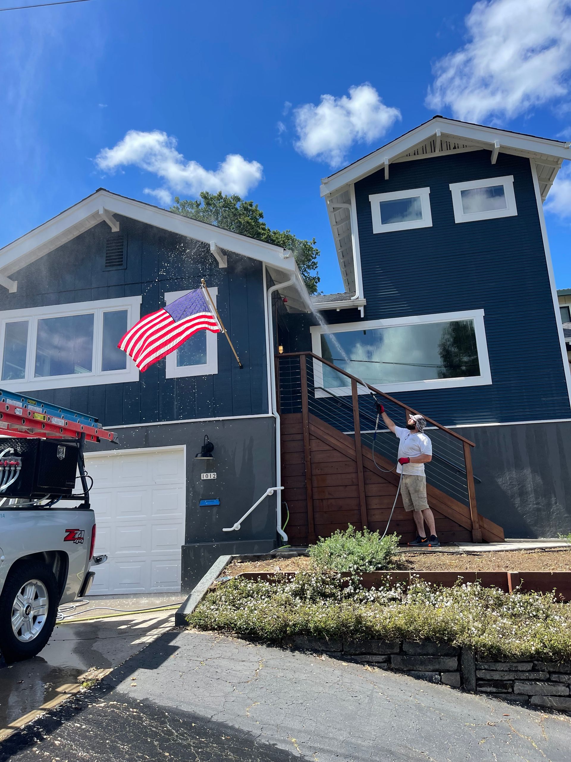 A man is cleaning the windows of a house with an american flag in the background