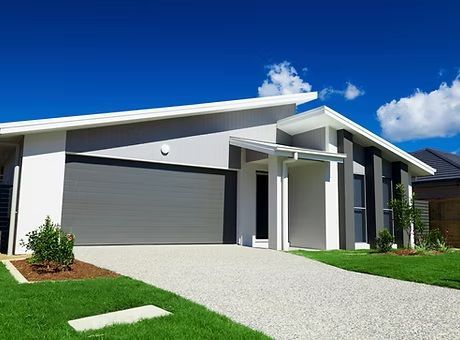 A white house with a gray garage door and a driveway
