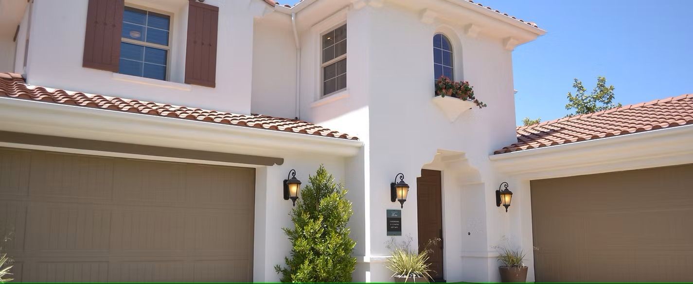 A large white house with two garage doors and a tiled roof