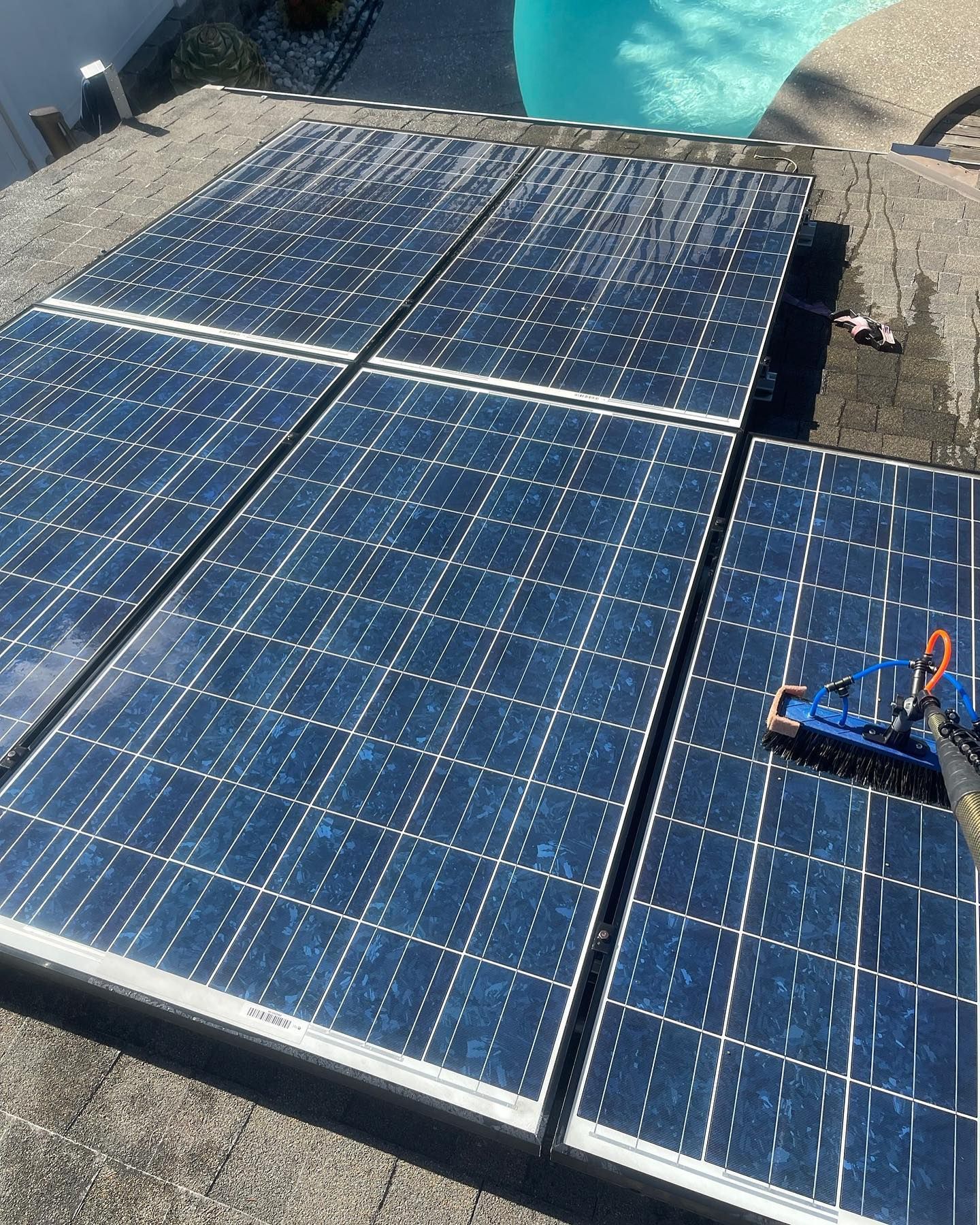 A group of solar panels are sitting on top of a roof next to a pool.